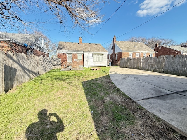 20561 Alcoy St, Detroit, MI 48205 - back of house featuring a lawn, driveway, a chimney, and a fenced backyard