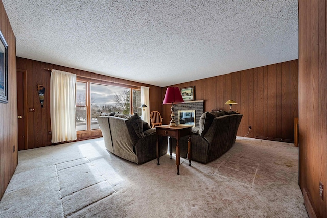 living area with carpet, wooden walls, a fireplace, and a textured ceiling