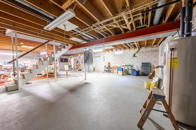 unfinished below grade area with stairs, concrete block wall, and gas water heater