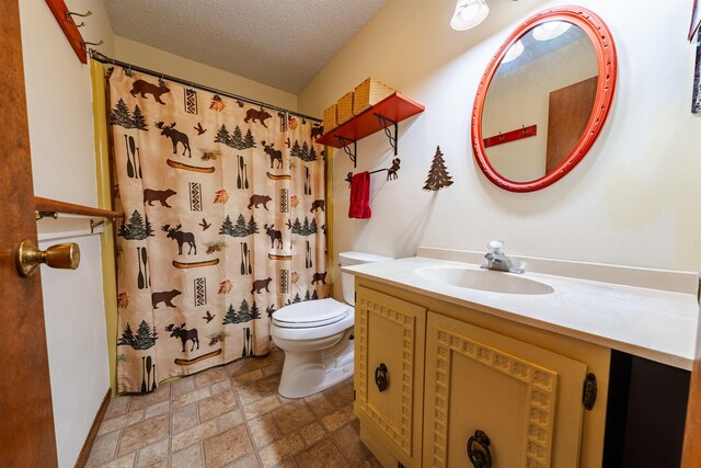 bathroom featuring vanity, stone tile floors, toilet, a shower with shower curtain, and a textured ceiling