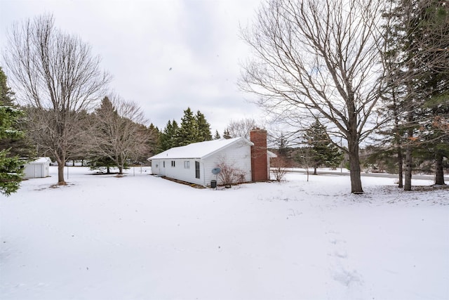 snow covered property featuring an outdoor structure and a chimney