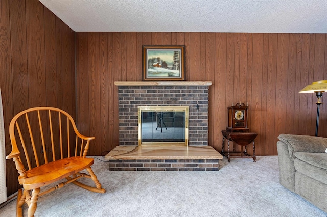 living area featuring carpet floors, a textured ceiling, wooden walls, and a brick fireplace
