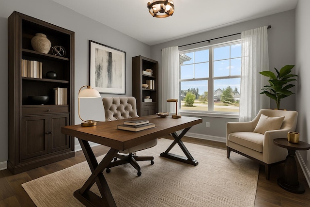 office area featuring baseboards, a notable chandelier, and wood finished floors