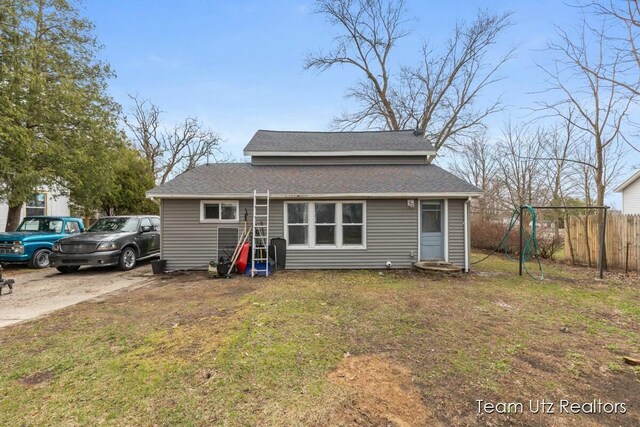 view of front of property featuring fence, a front lawn, and roof with shingles