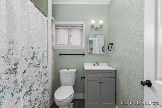 full bath with crown molding, toilet, vanity, a shower with curtain, and a textured wall