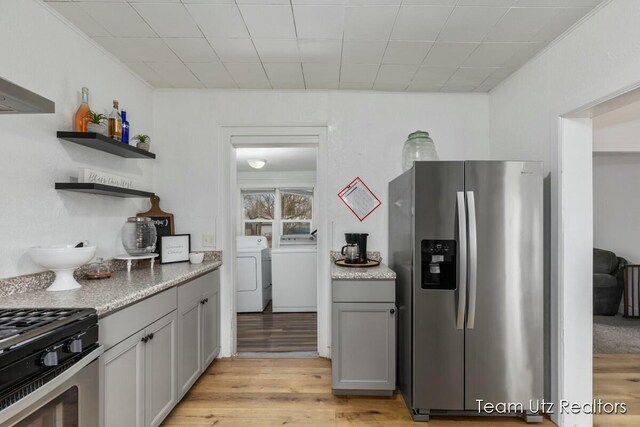 kitchen with open shelves, stainless steel appliances, gray cabinetry, light wood-style floors, and washing machine and dryer