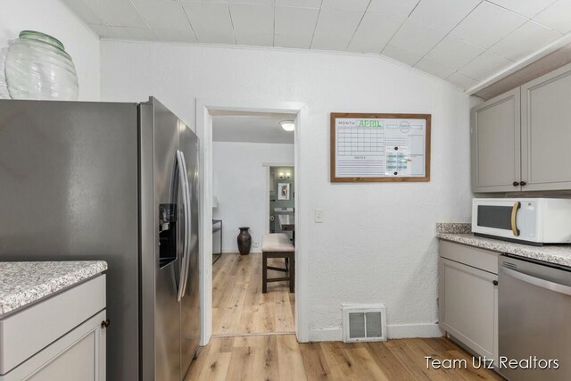 kitchen featuring gray cabinetry, visible vents, light wood-type flooring, and appliances with stainless steel finishes
