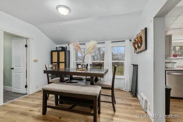 dining space with plenty of natural light, baseboards, lofted ceiling, and light wood-style floors