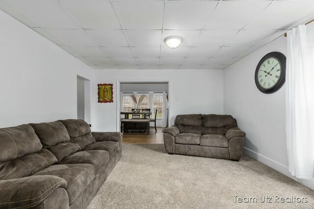 living room featuring baseboards and a drop ceiling