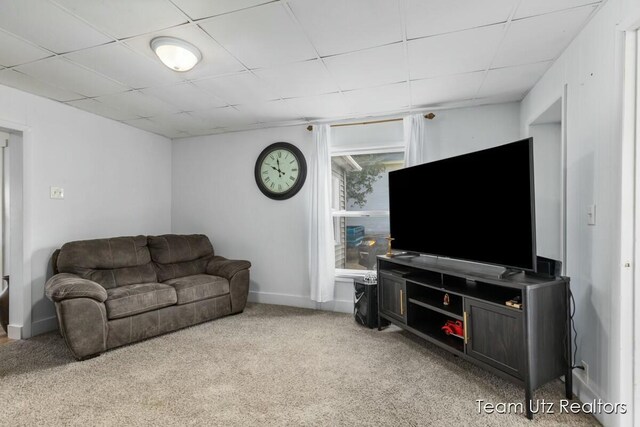 living area featuring baseboards, a paneled ceiling, and light colored carpet