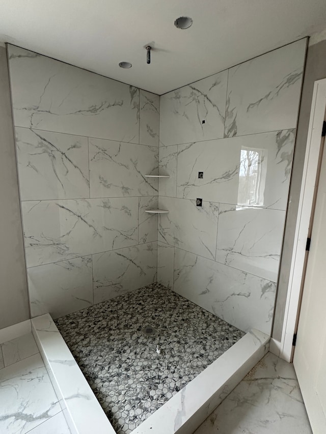 full bath with marble finish floor and tiled shower