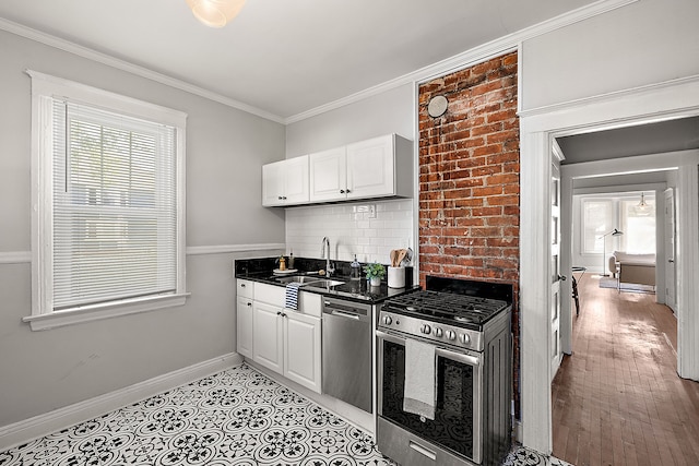 kitchen featuring stainless steel appliances, a sink, tasteful backsplash, white cabinets, and baseboards