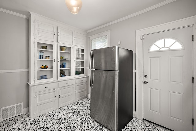 kitchen with freestanding refrigerator, ornamental molding, baseboards, and white cabinets