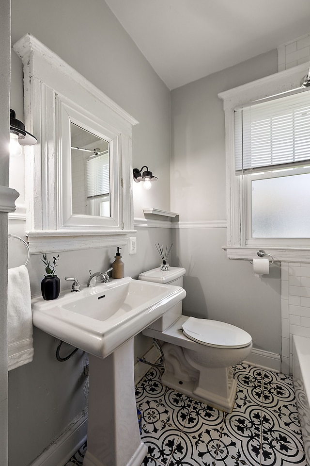 bathroom with toilet, tile patterned flooring, a bathtub, and baseboards