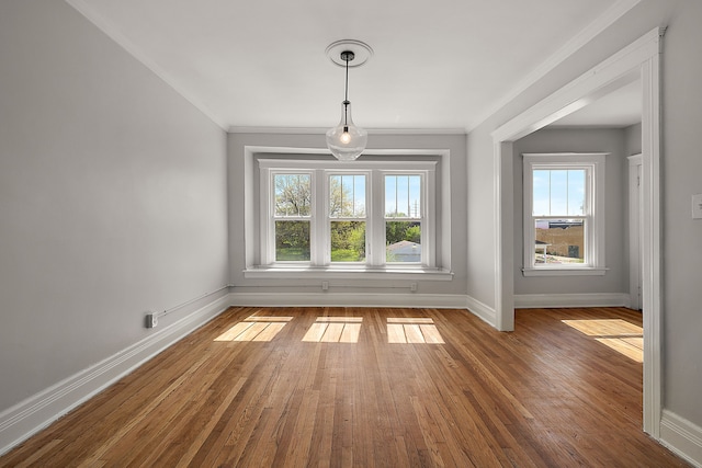 unfurnished dining area featuring crown molding, baseboards, and hardwood / wood-style flooring