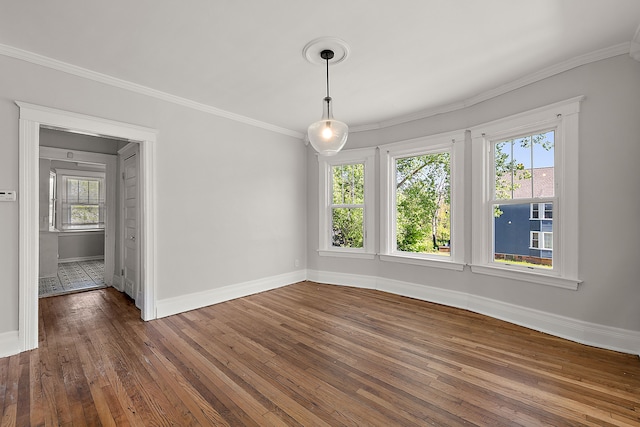 unfurnished dining area featuring dark wood finished floors, baseboards, and crown molding