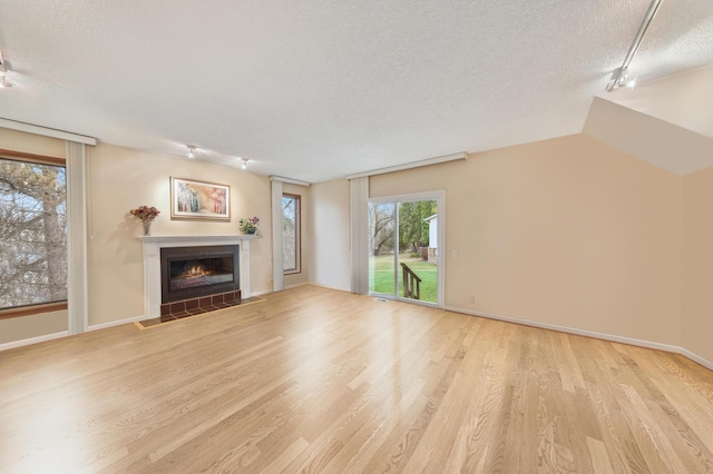 7465 Westbury Blvd, West Bloomfield, MI 48322 - unfurnished living room with a textured ceiling, wood finished floors, a glass covered fireplace, and baseboards