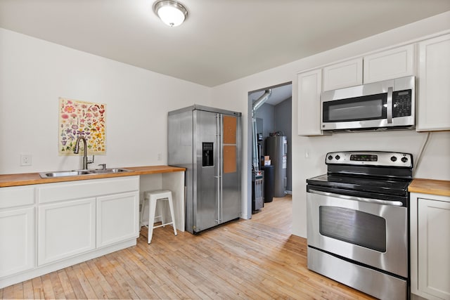 142 E Glass Rd, Ortonville, MI 48462 - kitchen featuring electric water heater, stainless steel appliances, a sink, wood counters, and light wood-style flooring