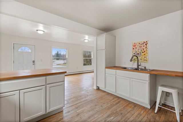 142 E Glass Rd, Ortonville, MI 48462 - kitchen featuring a sink, butcher block countertops, light wood-type flooring, white cabinets, and a baseboard heating unit