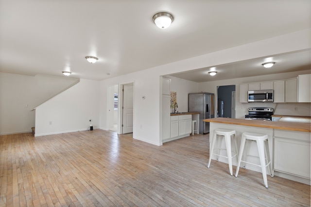 142 E Glass Rd, Ortonville, MI 48462 - kitchen with white cabinetry, open floor plan, butcher block countertops, stainless steel appliances, and light wood-style flooring