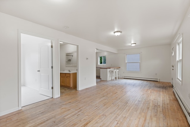 142 E Glass Rd, Ortonville, MI 48462 - unfurnished living room featuring baseboards, a sink, light wood-style floors, a baseboard radiator, and baseboard heating