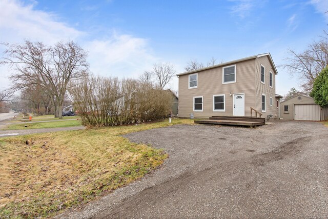 142 E Glass Rd, Ortonville, MI 48462 - view of front of home featuring driveway, an outbuilding, a deck, a front lawn, and a garage