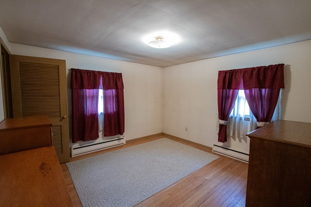 unfurnished bedroom with hardwood / wood-style floors, baseboards, and a baseboard radiator