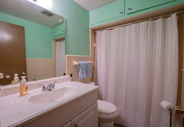 bathroom featuring tile walls, a wainscoted wall, visible vents, toilet, and vanity