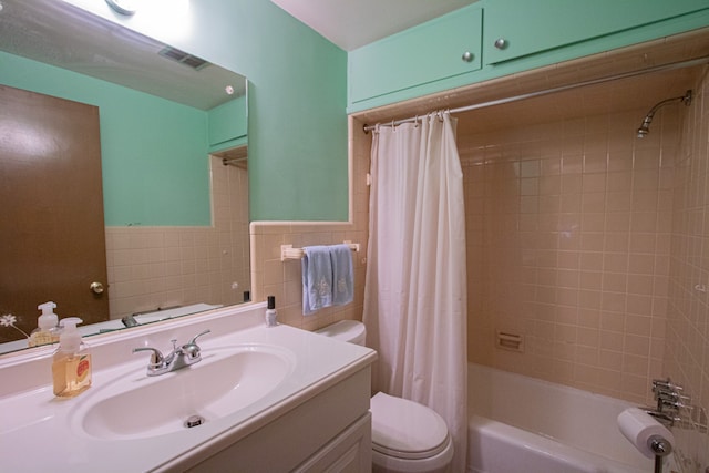 bathroom featuring tile walls, visible vents, toilet, vanity, and shower / bath combination with curtain