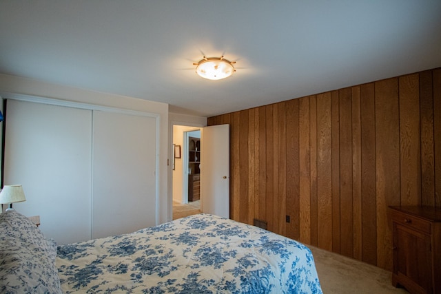carpeted bedroom featuring wood walls and a closet