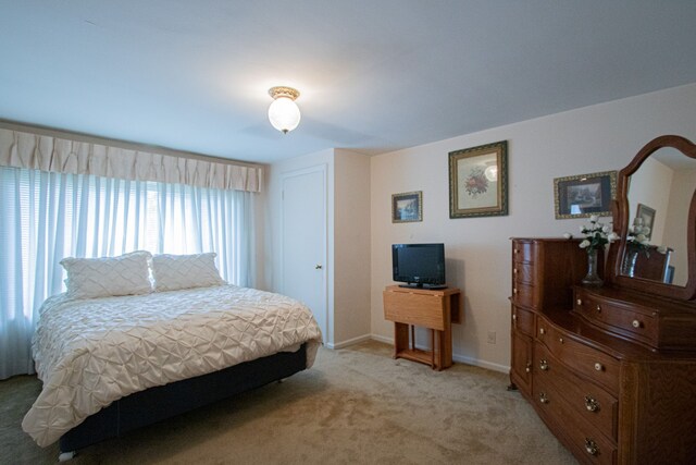 bedroom featuring light carpet and baseboards