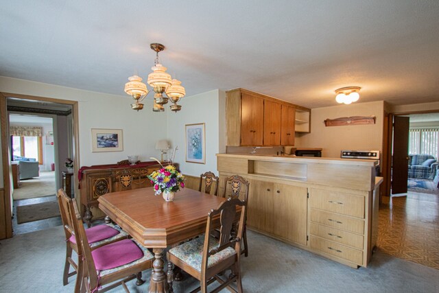 dining space with an inviting chandelier, plenty of natural light, and light colored carpet