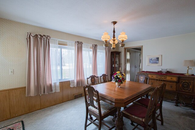 dining space with a wainscoted wall, carpet flooring, a chandelier, visible vents, and wallpapered walls