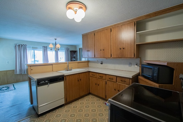 kitchen featuring wallpapered walls, black appliances, a sink, and an inviting chandelier