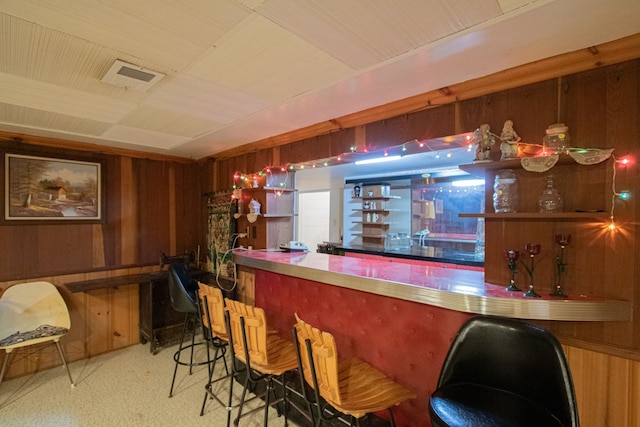 bar featuring a bar, visible vents, and wooden walls