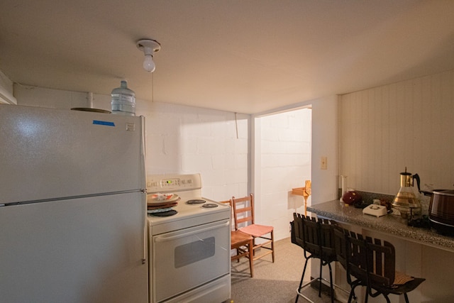kitchen with white appliances and concrete block wall