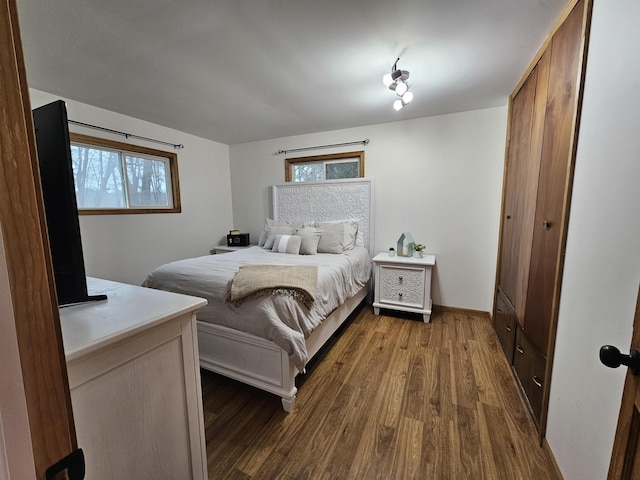 bedroom with dark wood finished floors and multiple windows
