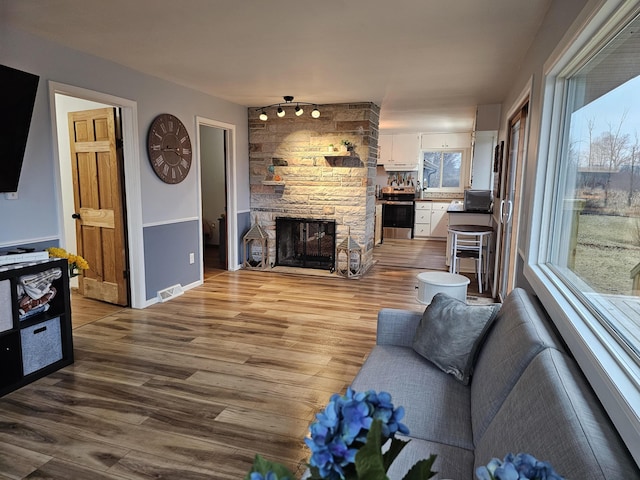 living room with baseboards, a fireplace, visible vents, and wood finished floors