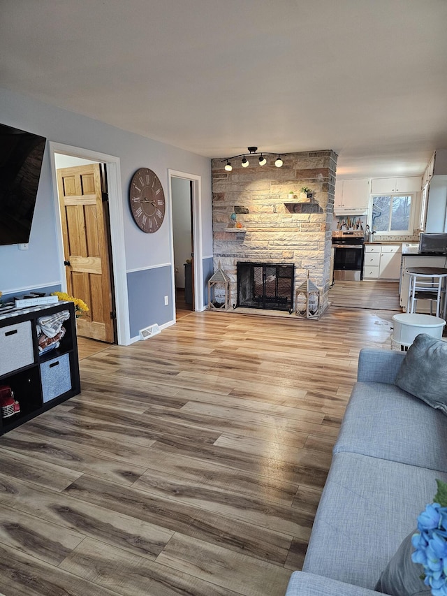 living area with a fireplace, visible vents, and light wood-type flooring