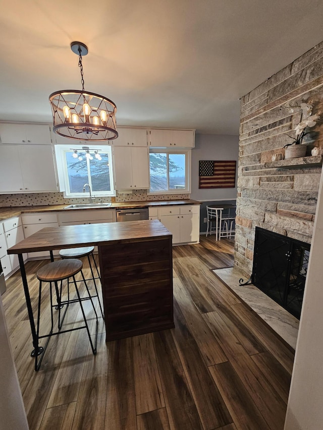 kitchen with white cabinetry, tasteful backsplash, an inviting chandelier, a sink, and dark wood-style floors