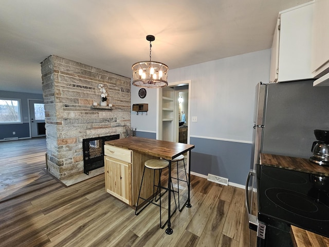 kitchen with butcher block countertops, visible vents, a fireplace, appliances with stainless steel finishes, and dark wood-style floors