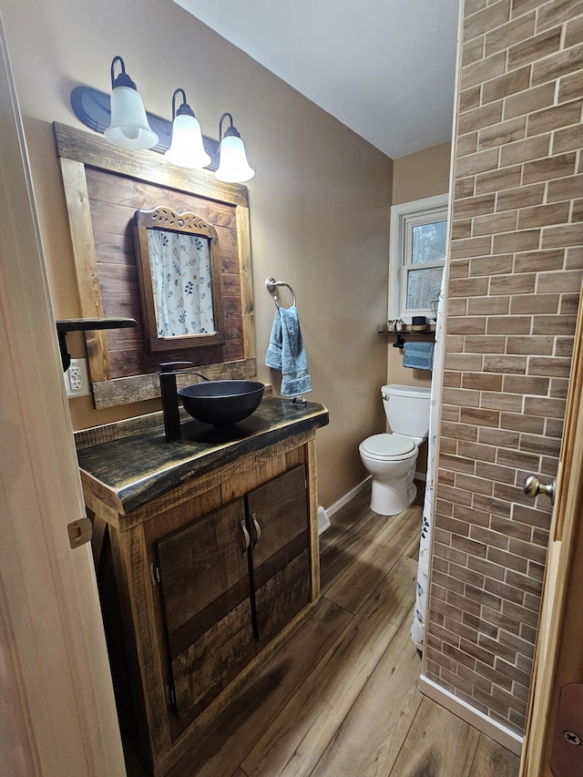 bathroom with toilet, wood finished floors, baseboards, and vanity