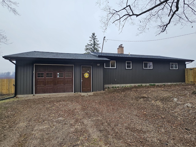 exterior space featuring fence, a chimney, and a garage