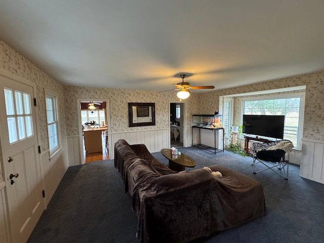 8162 Groveland Rd, Holly, MI 48442 - living room featuring wallpapered walls, a wainscoted wall, a ceiling fan, healthy amount of natural light, and carpet
