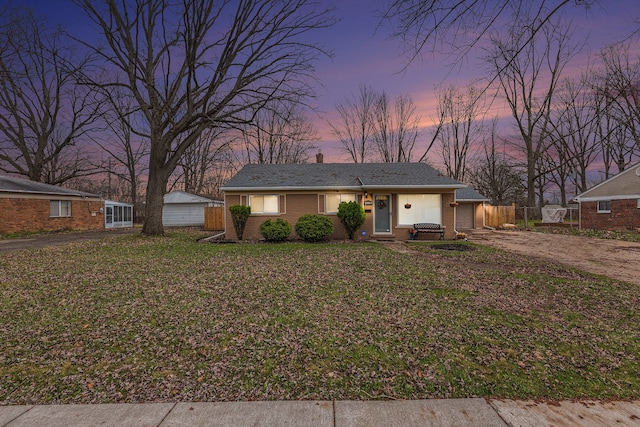 single story home featuring fence, dirt driveway, a front lawn, and an attached garage