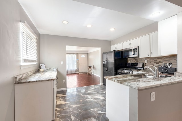 kitchen with white cabinetry, a sink, stainless steel appliances, and light stone countertops