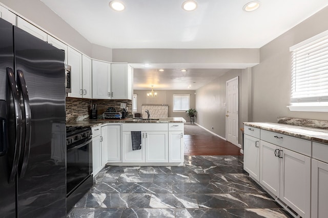 kitchen featuring black appliances, an inviting chandelier, a peninsula, and plenty of natural light