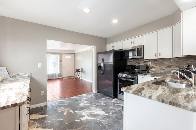 kitchen featuring white cabinets, a sink, backsplash, and appliances with stainless steel finishes