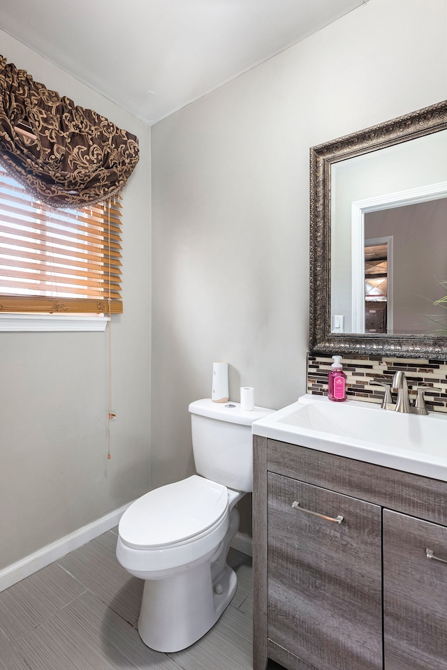 bathroom with tile patterned floors, toilet, vanity, tasteful backsplash, and baseboards