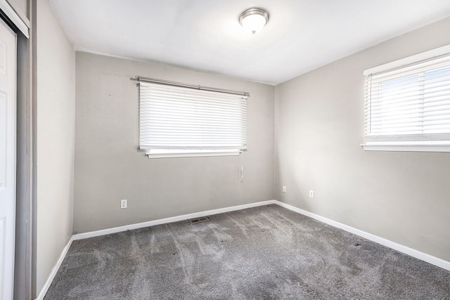 carpeted spare room with baseboards and visible vents